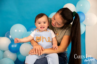 One year old baby boy Elijah sitting in a blue and white birthday photography setup