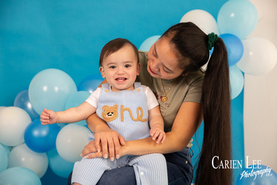 One year old baby boy Elijah sitting in a blue and white birthday photography setup