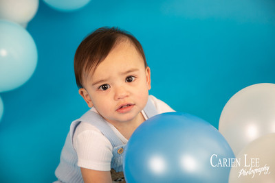One year old baby boy Elijah sitting in a blue and white birthday photography setup