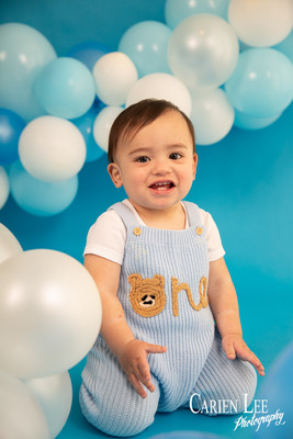 Baby boy celebrating turning one with a blue and white themed milestone photo session