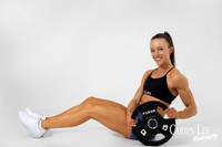 Woman seated beside a weight plate during a professional fitness photography session in Bunbury.